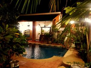 a swimming pool in front of a house with plants at Si Mi Capitán - Cabañas & Habitaciones in Puerto Iguazú