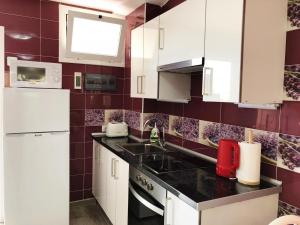 una cocina con armarios blancos y una pared de azulejos rojos en Lovely 1-bedroom apartment with a big terrace, Las Americas, Tenerife, en Arona