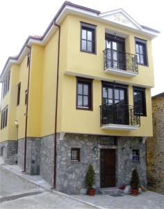 ein gelbes Haus mit schwarzen Fenstern und einer Steinmauer in der Unterkunft Casa La Kola Krusevo in Kruševo