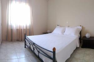 um quarto com uma cama com lençóis brancos e uma janela em Margaret's House em Kefalonia