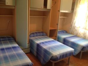 3 letti vuoti in una stanza con finestra di Villa Menazzi a Lignano Sabbiadoro