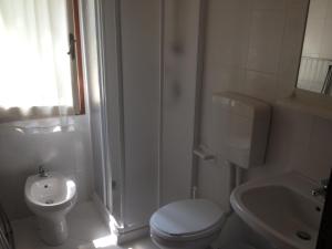 bagno bianco con servizi igienici e lavandino di Villa Menazzi a Lignano Sabbiadoro