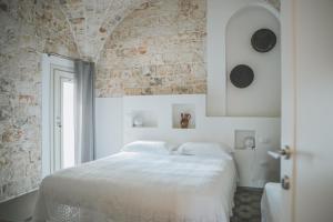 ロコロトンドにあるPietra Pesaraの白いベッドとレンガの壁が備わるベッドルーム1室が備わります。
