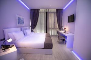 a bedroom with a white bed and a desk and a computer at Metro Hotel Tirana in Tirana