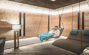 a man and a woman sitting on a swing in a room at Molaris Lodge in Mühlbach