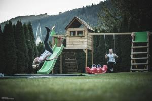 a person jumping off a slide on a playground at Molaris Lodge in Mühlbach