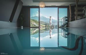 a woman standing on the edge of a swimming pool at Molaris Lodge in Mühlbach