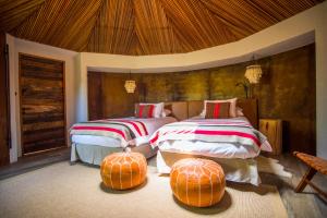 a bed room with two beds and a table at Hotel Desertica in San Pedro de Atacama