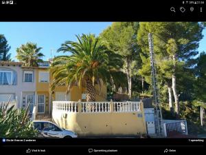 a white car parked in front of a building with palm trees at Casa Fleuri in La Nucía