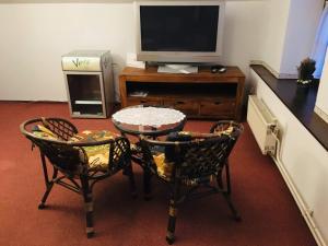 a living room with two chairs and a table and a tv at Penzion u modrého zvonku in Zlaté Hory