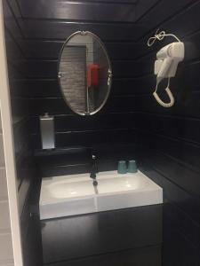 een zwarte badkamer met een wastafel en een spiegel bij Kuai Guestroom Brugge in Brugge