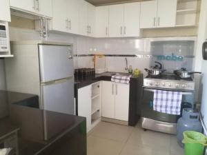 uma cozinha com armários brancos e um frigorífico de aço inoxidável em CASA F'BALUA em Tacna