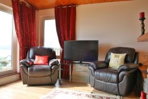 a living room with two chairs and a television at Ard na Carraige, Ventry Holiday Home in Dingle