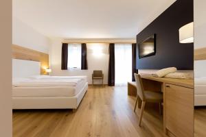 Habitación de hotel con cama y escritorio en Corona Dolomites Hotel, en Andalo