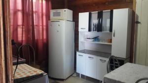 a white refrigerator with a microwave on top of it at Da Silva Chalé in São Lídio