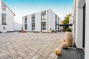 a courtyard with a white building and some plants at Naam Hotel & Apartments Frankfurt City-Messe Airport in Frankfurt/Main