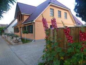 a house with a fence and pink flowers at Ferienwohnung Thum in Wustrow