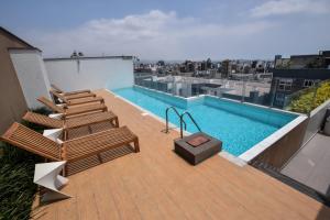 a deck with chairs and a swimming pool on a building at Miraflores Apartments 570 Pardo Ave by Private Host in Lima