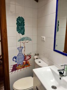 a bathroom with a toilet and a tree on the wall at La Casuca de Pumareña in Pumareña +20 photos