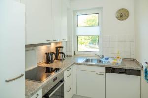 a kitchen with white cabinets and a sink and a window at Apartment Astra mit 2 Balkone in Zempin