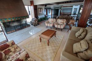 a living room with a couch and chairs and a fireplace at FLAT - Residencial Pousada do Serrano in Gramado