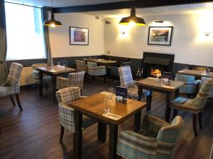 um restaurante com mesas e cadeiras e uma lareira em The Punchbowl Inn em Askham