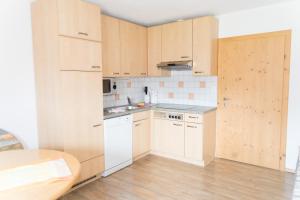 a kitchen with white appliances and wooden cabinets at Landhaus Rauth in Leutasch