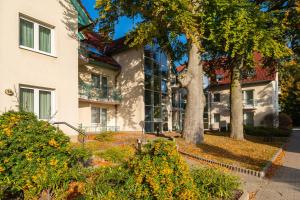 una casa blanca con árboles y arbustos delante de ella en Apartment Ostseerose ein Strandkorb ist im Sommer inclusive, en Zempin