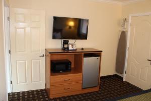 a television on top of a wooden stand with a refrigerator at Riverside Inn & Suites Santa Cruz in Santa Cruz