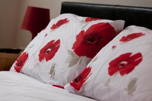 a bed with two pillows with red flowers on it at Lace Market Apartments - Nottingham City Centre most Central Location in Thurland Street - minutes to Motorpoint Arena and Victoria Centre Shopping Centre in Nottingham