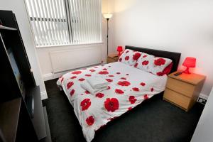 a bedroom with a bed with red flowers on it at Lace Market Apartments - City Centre - 4 Beds Apartment with 2 Bathrooms and full Kitchen in George Street - close to Victoria Centre Shopping Centre and the Mercure Hotel - Outdoor Parking for Cars or Vans at five pounds a day in Nottingham
