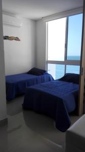 dwa niebieskie łóżka w pokoju z dużym oknem w obiekcie Apartamento con salida al Mar w mieście Santa Marta
