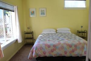 a bedroom with a bed with a colorful comforter and a window at Laughing Fish Studio in Mapua