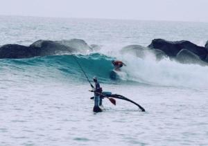 un uomo in piedi nell'oceano che tiene su una lenza di Aga Surf View a Tangalle