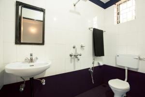 een badkamer met een wastafel, een toilet en een spiegel bij Crystall Goa, Onyx Edition in Palolem