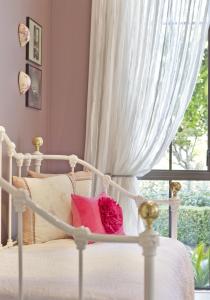 een wit bed met roze kussens en een raam bij Villa Te Soro Bed and breakfast in Auckland