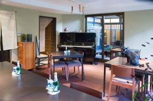 a living room with a piano and tables and chairs at Yadoya Nishijinso in Kyoto