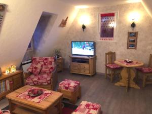 ein Wohnzimmer mit einem TV sowie Tischen und Stühlen in der Unterkunft Chambre d'hôtes l'Olivianne in Sarlat-la-Canéda