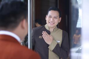 a man standing in front of a mirror at Midtown Hotel Surabaya in Surabaya