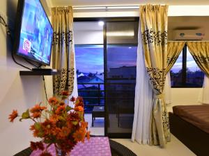 Anahaw Apartments Whitebeach في بوراكاي: غرفة معيشة فيها تلفزيون وطاولة فيها ورد