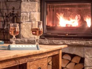 two glasses of wine on a table in front of a fireplace at Chalet Chardons Belvedere in Tignes