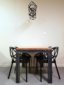 a black dining table with black chairs and aendant light at Nowoczesny Apartament w Centrum in Kościerzyna