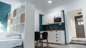 ブダペストにあるBpR Downtown Gemstone Apartmentsの白いキャビネット、テーブルと椅子付きのキッチンが備わります。