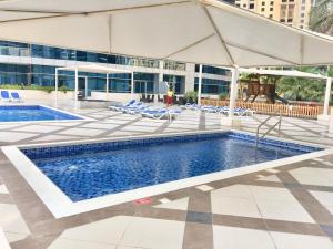 a pool with chairs and an umbrella next to a building at Icon Casa Living - Bay Central Tower in Dubai
