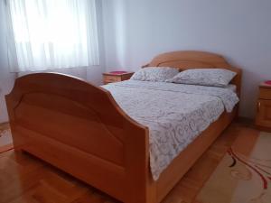 - une chambre avec un grand lit et une tête de lit en bois dans l'établissement Apartment Caka, à Zlatibor