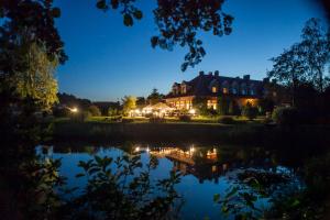 una casa con un estanque delante de ella por la noche en Hubertus Aparthotel & Restaurant & Horse Club, en Starogard Gdański