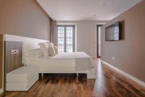 a white bedroom with a bed and a tv at Hommyhome Arenal Luxury in Seville