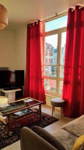 salon z czerwonymi zasłonami i dużym oknem w obiekcie T2 SUR LES PLACES w mieście Arras