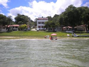Cobertura paraiso Cacoes في Jaguaripe: مجموعة من الناس يجلسون على شاطئ بجوار الماء