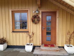 drzwi wejściowe domu z dwoma doniczkami w obiekcie Ferienwohnung Grimmingblick w mieście Bad Mitterndorf